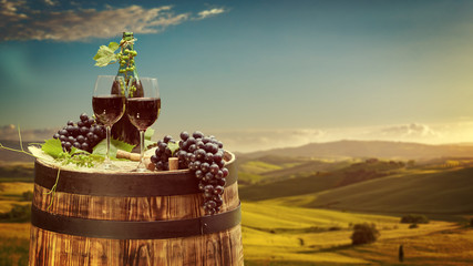 Wall Mural - Red wine bottle and wine glass on wodden barrel. Beautiful Tuscany background