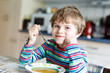 © Irina Schmidt - Adorable little school boy eating vegetable soup indoor.