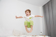 Cheerful little boy  jumping on bed at home.