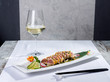 Dish of cooked tuna fish sushi-style with a glass of white wine