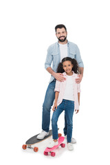 Wall Mural - Happy father and daughter standing with skateboards and smiling at camera