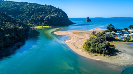 Aerial view on a river mouth with residential suburb on the shore and ocean with small islands on the background. Auckland, New Zealand