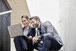 © Westend61 - Businessman and businesswoman sitting on stairs in office sharing laptop
