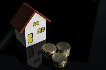 Little house model and coin on glass table for banking and finance concept