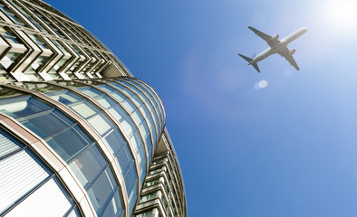 Plane flying above modern office building.