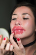 Beautiful natural girl woman aplying a lips pink mask, spa treatments. Cosmetology in a dark background