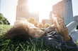 © goodluz - Portrait of mixed race girl laying in park using smartphone