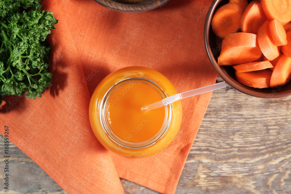 Jar of carrot juice on wooden table