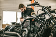 Motorcycle mechanic repairing electronics sports black bike. Handsome mechanic working in auto repair shop.