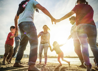 Diverse culture families playing with children on the beach - Sons and parents ringing around the rosie on summer vacation - Travel , holidays concept - Focus on girl with back light - Contrast filter