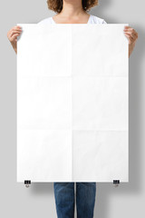 Woman holding a blank A1 poster mockup isolated on a gray background. 