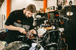 Professional motorcycle mechanic works with electronics, cuts wires. Handsome mechanic working in bike repair shop.