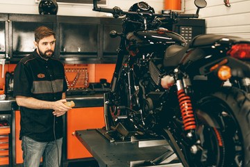 Wall Mural - Professional moto mechanic raises a motorcycle on the lift. Man pressing up and down switch in bike repair shop.