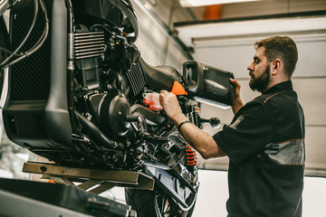 Wall Mural - Motorcycle mechanic replacing and pouring fresh oil into engine at maintenance repair service station. Portrait of an auto mechanic putting oil in a car engine.