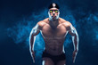 Attractive and muscular swimmer. Studio shot of young shirtless sportsman on black smoke background. Man with glasses