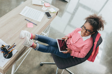 Wall Mural - overhead view of little african american businesswoman in eyeglasses using digital tablet in office