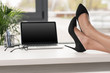 © LIGHTFIELD STUDIOS - cropped shot of  businesswoman legs crossed on table near laptop and eyeglasses