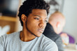 © Iryna - Melancholic headshot portrait of young black man looking aside isolated on blurred indoors background.