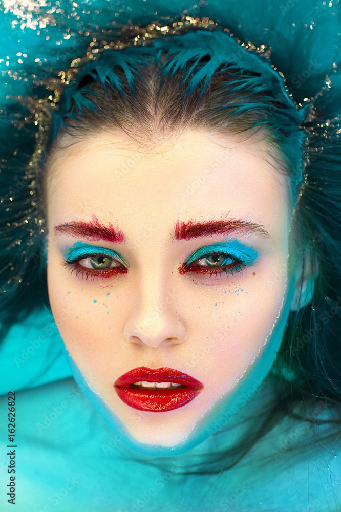 Beautiful woman laying in water with bright glamour make up.  - obrazy, fototapety, plakaty 