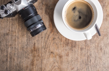 high-angle shot of a white ceramic cup with white coffee and camera of a rustic wooden table