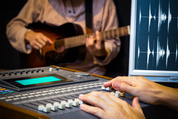 Wall Mural - sound engineer hands working on digital sound mixer for acoustic guitar recording in music studio