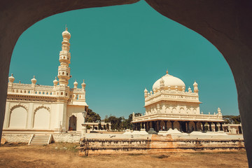 Wall Mural - View from arch on the tall stone minaret and historical Tipu Sultan Gumbaz in Srirangapatna, India. 18th century Muslim mausoleum.