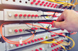 Engineer is setting up industrial optical telecommunications switchboard