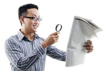 Canvas Print - Asian man reading newspaper with magnifier