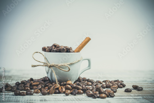 laska-cynamonu-i-biala-filizanka-z-ziarenkami-kawy-na-bialym-tle-na-drewnianym-stole