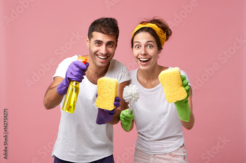 Fotografía Positive male and female from service cleaning holding brush, spray and sponges