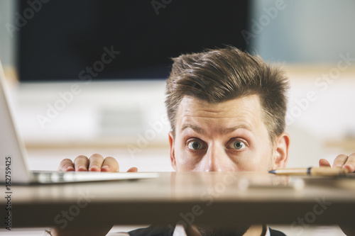 Fotomural Crazy man hiding behind table