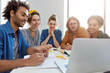 © wayhome.studio  - Horizontal portrait of group of mixed race students working together at project trying to relax for a minute and to watch funny videos over laptop computer. Interracial friends making presentation