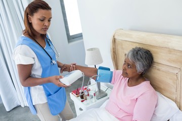 Wall Mural - Doctor measuring blood pressure of senior woman 