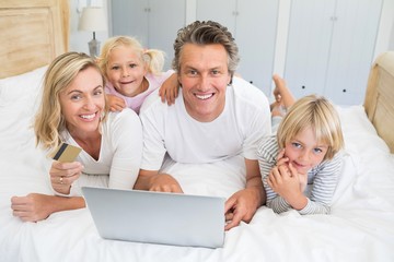 Wall Mural - Happy family doing online shopping on laptop in the bed room