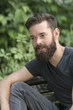 © cineberg - Handsome thoughtful bearded guy sitting on a bench in park