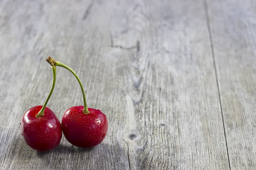 Bright ripe cherry on a gray wooden background.