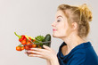 Woman holds shopping basket with vegetables, smelling