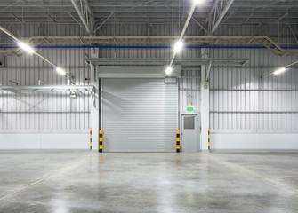 Roller door or roller shutter inside factory, warehouse or industrial building. Modern interior design with polished concrete floor and empty space for product display or industry background.