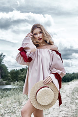 Wall Mural - Sexy blond woman perfect body shape pretty face makeup wear collection casual designer dress accessory straw hat skyline beauty landscape of summer nature sand river tree sky cloud weather vocation.