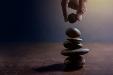 Balance Concept Between Of Life And Work Present By Hand Setting A Natural Zen Rock Stone On Stack, Side View And Dark Light