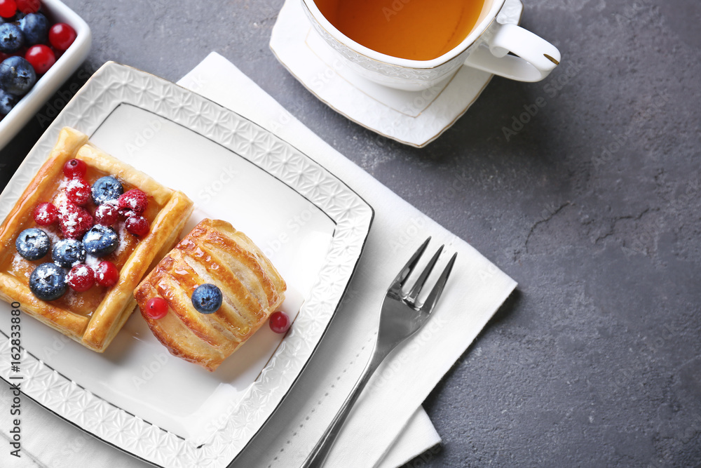 Plate with delicious puff pastries and berries on served table