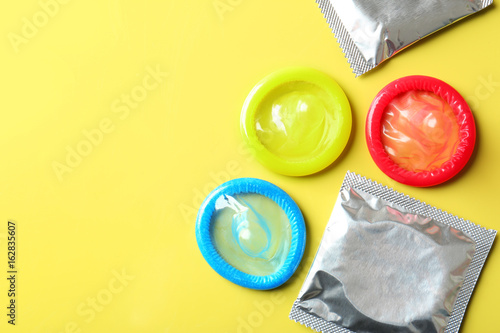 Fotografía Open and wrapped condoms on color background. Safe sex concept