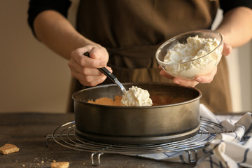 Woman preparing cheese cake in kitchen