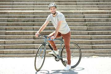 Handsome young man riding bicycle outdoors on sunny day