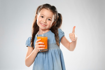 Wall Mural - Cute little girl with glass of juice on light background