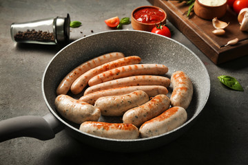 Poster - Grey frying pan with delicious grilled sausages on kitchen table