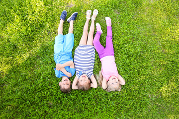 Canvas Print - Cute little children lying on green grass in park