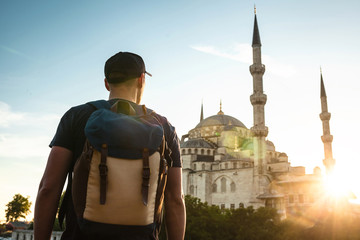 A man in a baseball cap with a backpack next to the blue mosque is a famous sight in Istanbul. Travel, tourism, sightseeing.