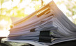 Stack of documents and paperwork files on work desk in business office with light blur background
