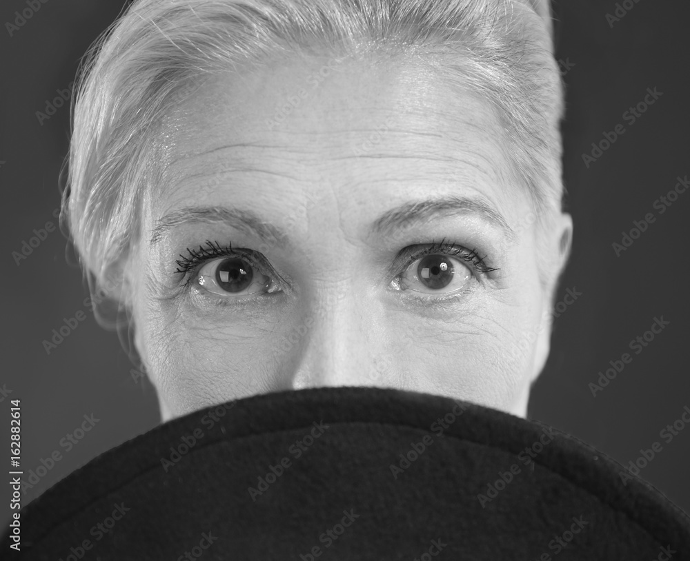Beautiful elderly woman with hat on dark background, black and white